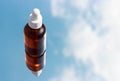 Glass bottle with serum on background of clouds and sky close-up.