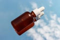 Glass bottle with serum on background of clouds and sky close-up.