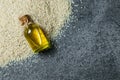 Glass bottle of sesame oil and raw sesame seeds on grey rustic table Royalty Free Stock Photo