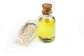 Glass bottle of sesame oil and raw sesame seeds in wooden shovel isolated on white background Royalty Free Stock Photo