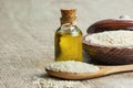 Glass bottle of sesame oil and raw sesame seeds in wooden shovel or spoon and in bowl on burlap sack Royalty Free Stock Photo