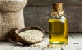 Glass bottle of sesame oil and raw sesame seeds in wooden shovel or spoon on burlap sack Royalty Free Stock Photo