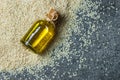 Glass bottle of sesame oil and raw sesame seeds on grey rustic table Royalty Free Stock Photo