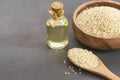 Glass bottle of sesame oil and raw sesame seeds in wooden shovel with burlap sack on wooden table Royalty Free Stock Photo