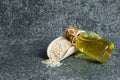Glass bottle of sesame oil and raw sesame seeds in wooden shovel on grey rustic table Royalty Free Stock Photo