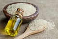 Glass bottle of sesame oil and raw sesame seeds in wooden shovel or spoon and in bowl on burlap sack Royalty Free Stock Photo