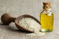 Glass bottle of sesame oil and raw sesame seeds in wooden shovel or spoon on burlap sack Royalty Free Stock Photo