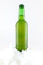 Glass bottle on the snow. Condensation on the bottle. Chilled drink in a glass bottle. On a white background