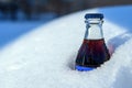 Glass bottle of soda coke stuck in snow snow snow snow in sunset light