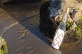 Glass bottle with SOS message near sea rocks, space for text