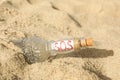 Glass bottle with SOS message on sand, closeup Royalty Free Stock Photo