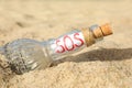 Glass bottle with SOS message on sand, closeup Royalty Free Stock Photo