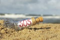 Glass bottle with SOS message on sand near sea, closeup Royalty Free Stock Photo