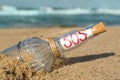 Glass bottle with SOS message on sand near sea, closeup Royalty Free Stock Photo