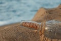 Glass bottle with SOS message on sand near sea, space for text Royalty Free Stock Photo