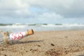 Glass bottle with SOS message on sand near sea, space for text Royalty Free Stock Photo