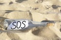 Glass bottle with SOS message on sand outdoors Royalty Free Stock Photo