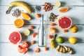 Glass bottle surrounded by different fruits and nuts on the white wooden table top view