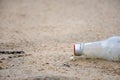 Glass bottle throw on the sand by human in the beach Royalty Free Stock Photo