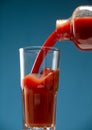 Glass and bottle of tomato juice isolated on blue background. Royalty Free Stock Photo