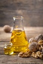 Glass bottle with walnut oil and walnut kernel on a wooden table.