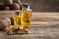 Glass bottle with walnut oil and walnut kernel on a wooden table.