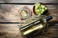 Glass and bottle of white wine with fresh grapes on wooden table Royalty Free Stock Photo