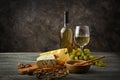 Glass and bottle of white wine with snacks and ripe grapes on wooden table Royalty Free Stock Photo