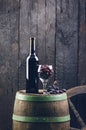 Glass and bottle of wine on a wooden barrel. Burnt, black wooden background. Vintage. Copyspace for a text. Grapes and green vine. Royalty Free Stock Photo