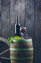 Glass and bottle of wine on a wooden barrel. Burnt, black wooden background. Vintage. Copyspace for a text. Grapes and green vine. Royalty Free Stock Photo