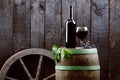 Glass and bottle of wine on a wooden barrel. Burnt, black wooden background. Vintage. Copyspace for a text. Grapes and green vine. Royalty Free Stock Photo