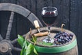 Glass and bottle of wine on a wooden barrel. Burnt, black wooden background. Vintage. Copyspace for a text. Grapes and green vine. Royalty Free Stock Photo