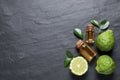 Glass bottles of bergamot essential oil and fresh fruits on black slate table, flat lay. Space for text Royalty Free Stock Photo