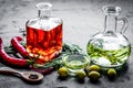 Bottles with chili and olive oils and herbs on stone background