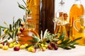 Glass bottles and carafes with fresh olive oil on wooden table with olive branches and fresh olives Royalty Free Stock Photo