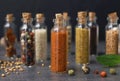 Glass bottles with different spices on table against dark background Royalty Free Stock Photo