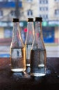 Glass bottles filled with half water in neon light on the background of the view from the window. Selective focus Royalty Free Stock Photo