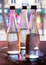 Glass bottles filled with half water in neon light on the background of the view from the window. Selective focus Royalty Free Stock Photo