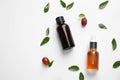 Glass bottles with jojoba oil and seeds on white background