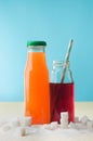 Glass bottles with orange and cherry juice near sugar