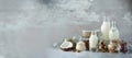 Glass bottles of vegan plant milk and almonds, nuts, coconut, hemp seed milk on grey concrete background. Banner with copy space.