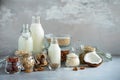 Glass bottles of vegan plant milk and almonds, nuts, coconut, hemp seed milk on grey concrete background. Banner with copy space. Royalty Free Stock Photo