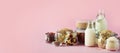 Glass bottles of vegan plant milk and almonds, nuts, coconut, hemp seed milk on pink background. Banner with copy space. Dairy