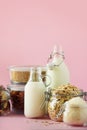 Glass bottles of vegan plant milk and almonds, nuts, coconut, hemp seed milk on pink background. Banner with copy space. Dairy Royalty Free Stock Photo