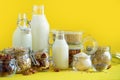 Glass bottles of vegan plant milk and almonds, nuts, coconut, hemp seed milk on yellow background. Banner with copy space. Dairy