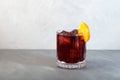 Glass of Boulevardier cocktail with big ice cubes and orange slice. Classic alcoholic drink composed of whiskey, sweet vermouth,