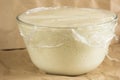 Glass bowl with aired yeast dough raised covered by the cling film Royalty Free Stock Photo