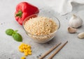 Glass bowl of boiled long grain basmati vegetable rice on light table background with sticks and red paprika with corn, garlic and