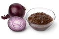 Glass bowl with caramelized red onion chutney and a fresh red onion on the side close up