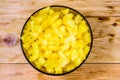 Glass bowl with chopped pineapple on wooden table. Top view